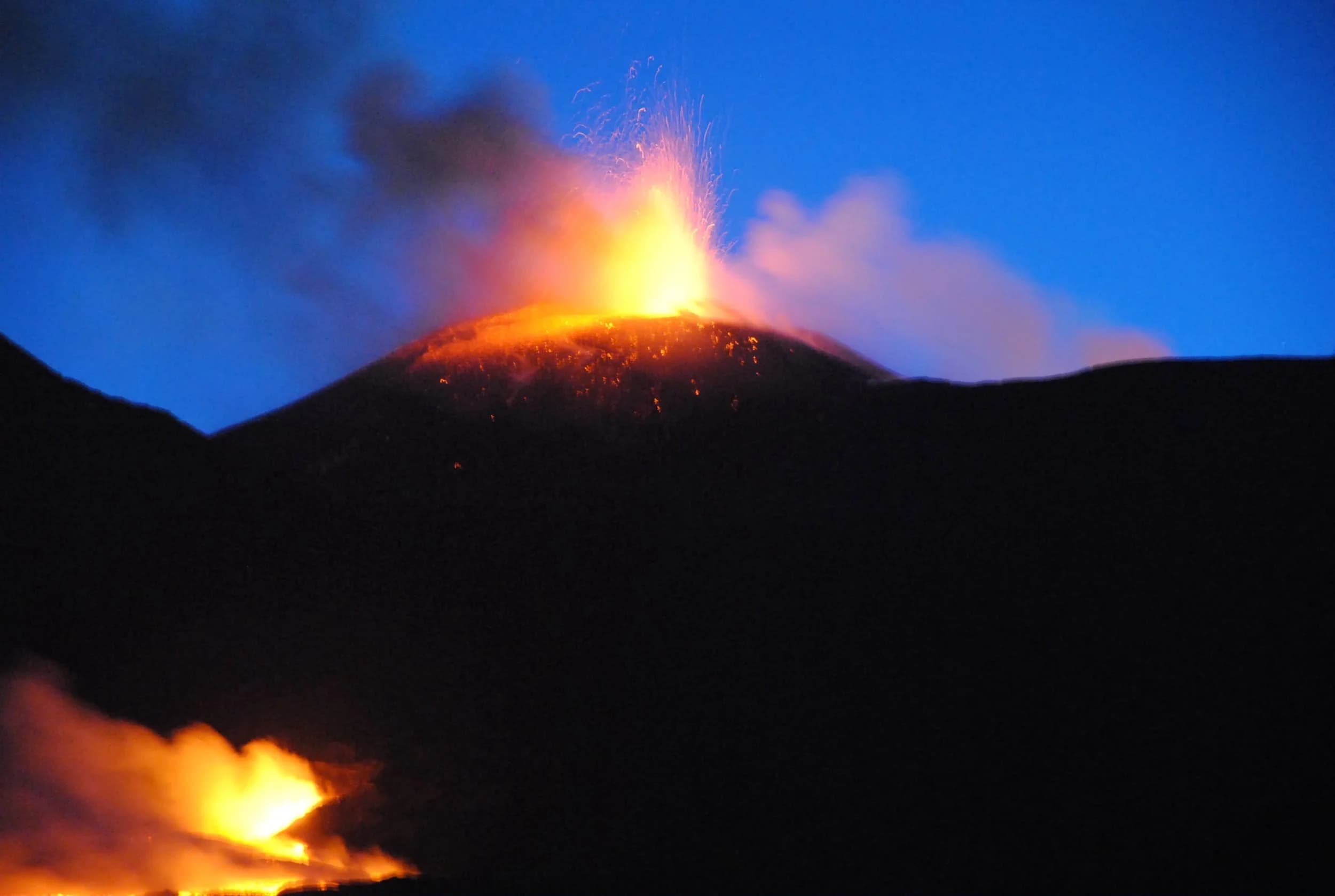 Eruzione notturna: fontana di lava dal cratere e colata incandescente