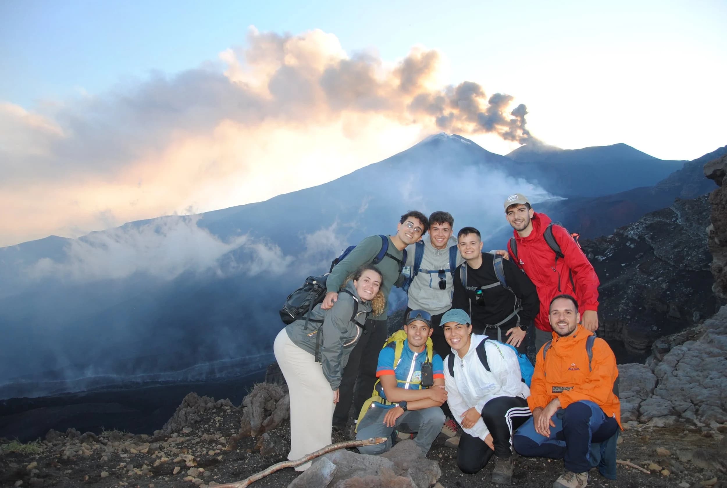 Gruppo di escursionisti al tramonto davanti all'eruzione in corso