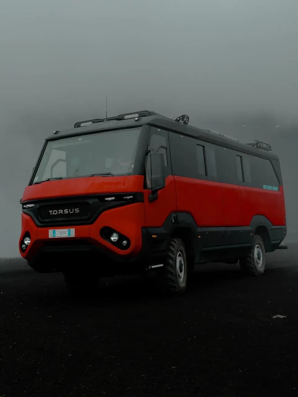 Il bus 4x4 rosso fermo sulla cenere, avvolto dalla nebbia di quota